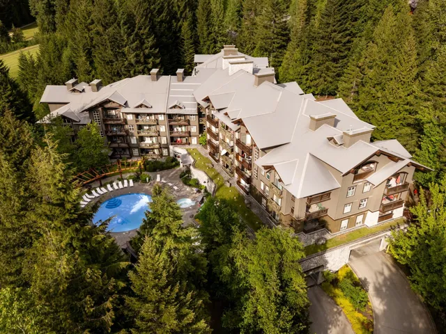 Multi-story residential building featuring a gray roof, multiple balconies, a swimming pool, and a separate spa
