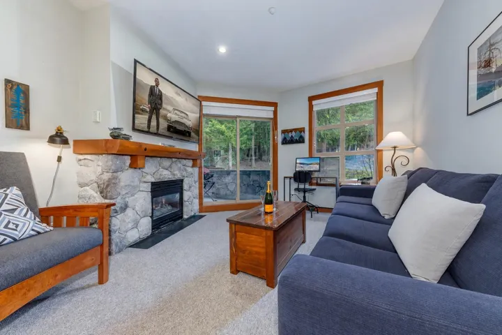 Living area featuring a stone fireplace with a wood mantle, carpet flooring, and recessed lighting