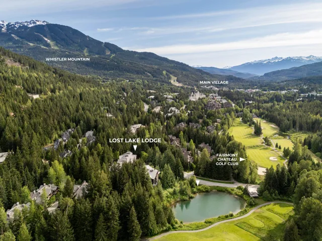 Aerial perspective of a mountain landscape featuring extensive tree coverage, a tranquil lake, and a golf course