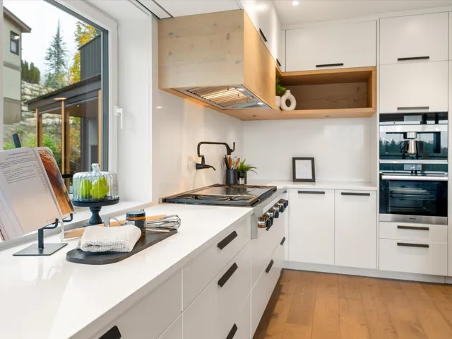 Kitchen with white cabinets, modern cabinets, light wood finished floors, stainless steel appliances, and exhaust hood