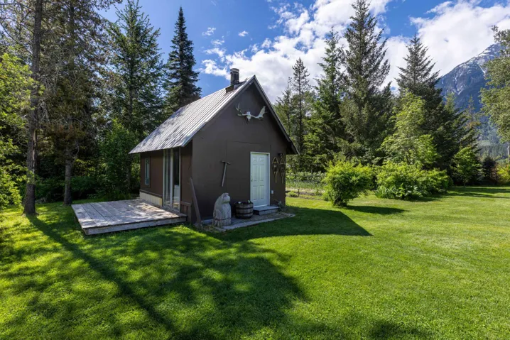 Charming outbuilding featuring a metal roof, wood siding, and an exterior deck