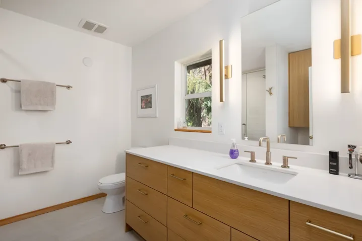 Bathroom featuring a light wood-finish vanity with drawer storage, white countertop, and under-mount sink