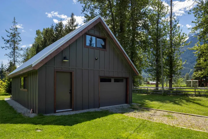 Gable-roof structure featuring board and batten siding, a metal roof, and a single garage door
