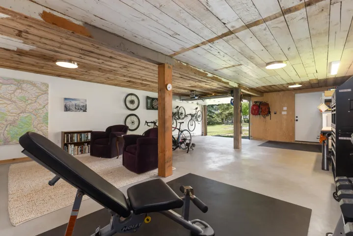 Spacious multi-purpose room featuring a wood-plank ceiling, concrete flooring, and exposed structural beams