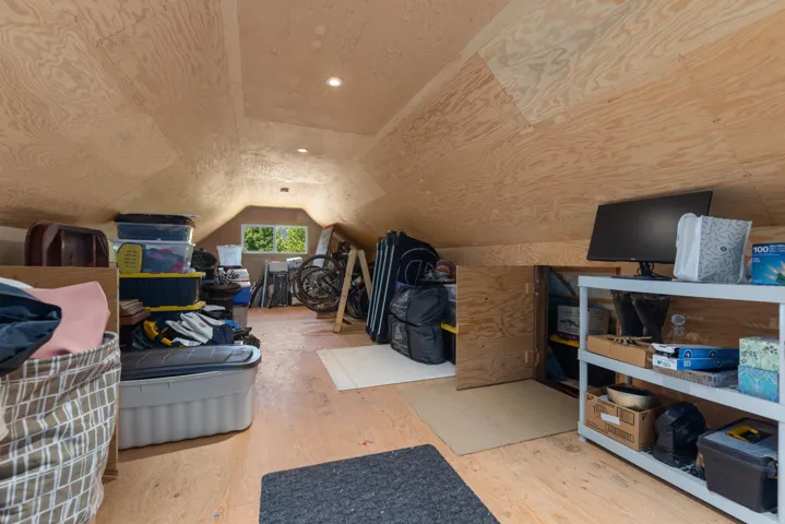 Plywood finished attic space featuring sloped ceilings, recessed lighting, and a dormer window