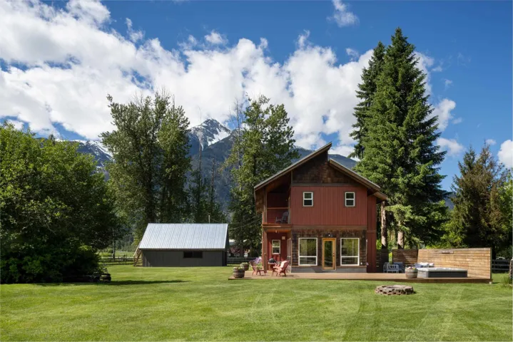 Red wood-sided residence featuring a multi-level wood deck with an integrated hot tub