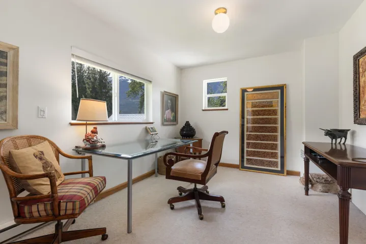 Carpeted room featuring multiple windows, a glass-top desk, and a built-in ceiling light fixture
