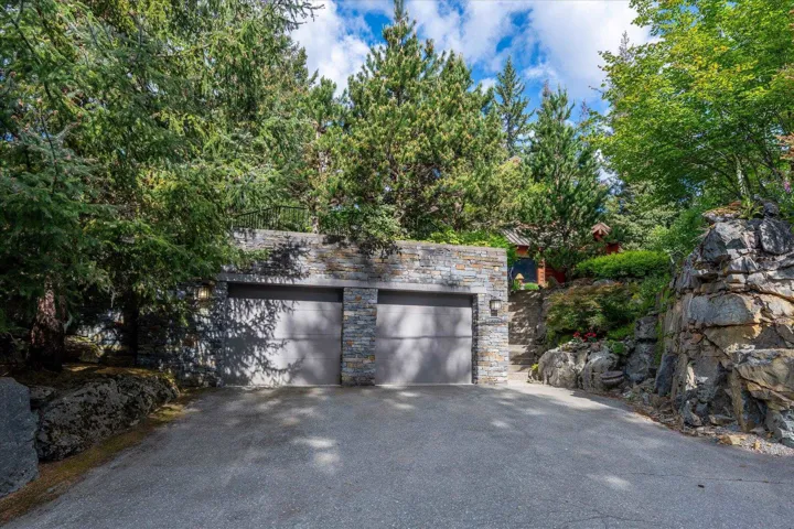 Two-car garage with stacked stone facade and concrete driveway