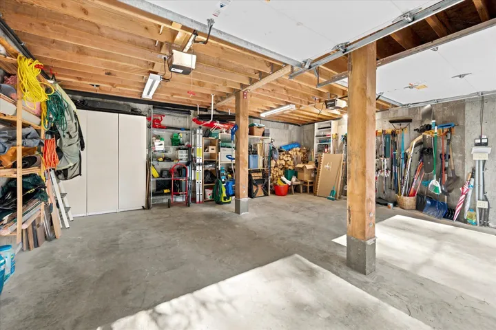 Spacious garage featuring a concrete floor, exposed wood ceiling joists, and a concrete foundation wall