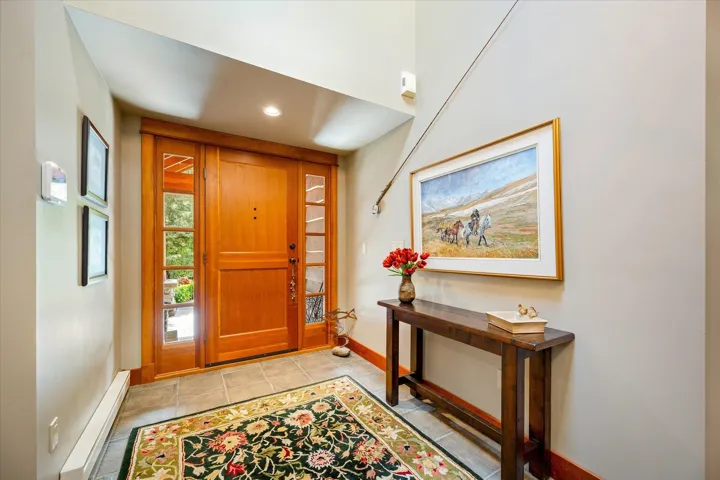 Entryway featuring a wood-panel door with sidelight windows, tile flooring, and neutral wall tones