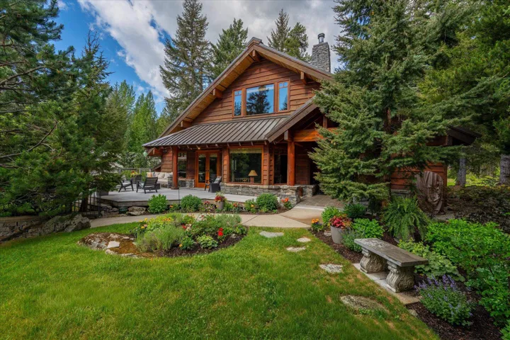 Wood-sided home featuring a stone chimney, metal roof, and exposed wood beam accents