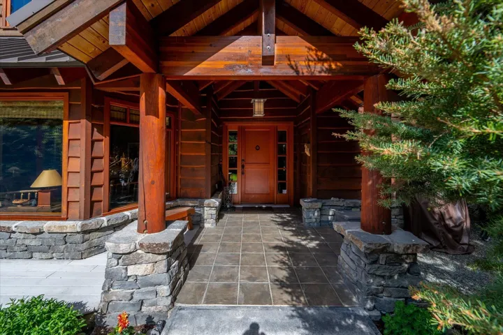 Architectural wood-frame entry featuring a covered porch with exposed beams, wood-plank siding, and a solid wood front door