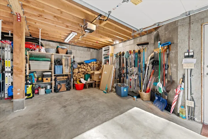 Spacious garage with concrete flooring, exposed wood beam ceiling, and a large garage door