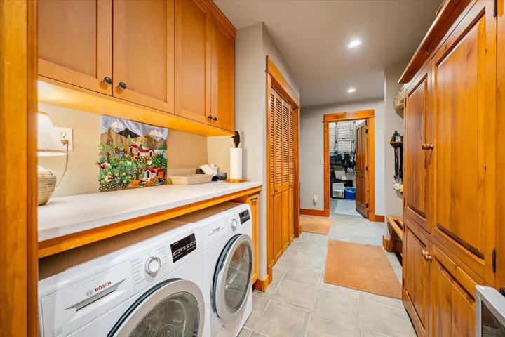 Laundry area featuring custom wood cabinetry, a white countertop, and under-cabinet lighting