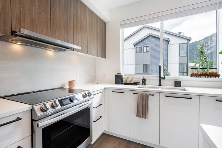 Kitchen with electric stove, modern cabinets, exhaust hood, and plenty of natural light