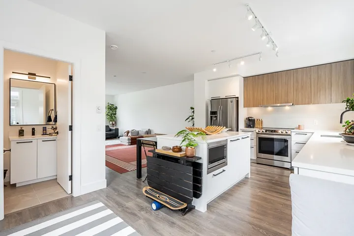 Kitchen with backsplash, stainless steel appliances, light wood finished floors, modern cabinets, and white cabinetry