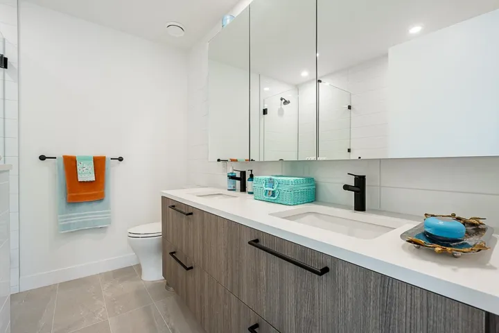 Bathroom with double vanity, a tile shower, and recessed lighting