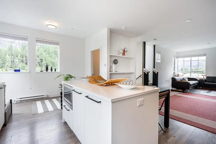 Kitchen featuring light countertops, white cabinets, dark wood-type flooring, and modern cabinets