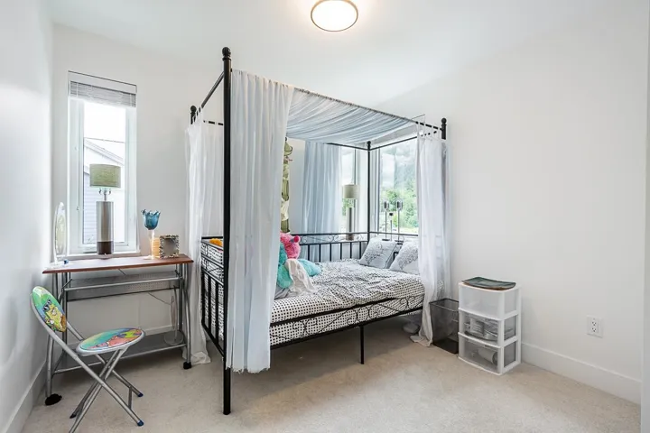Bedroom featuring multiple windows and light carpet