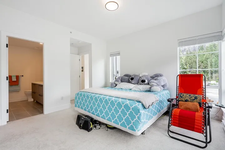 Bedroom with multiple windows, light carpet, and connected bathroom