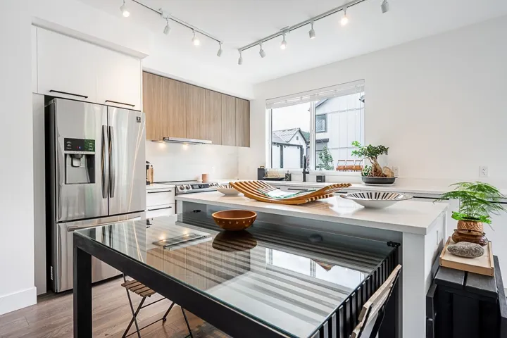 Kitchen featuring stainless steel appliances, dual tone cabinets, modern cabinets, light wood finished floors, and track lighting
