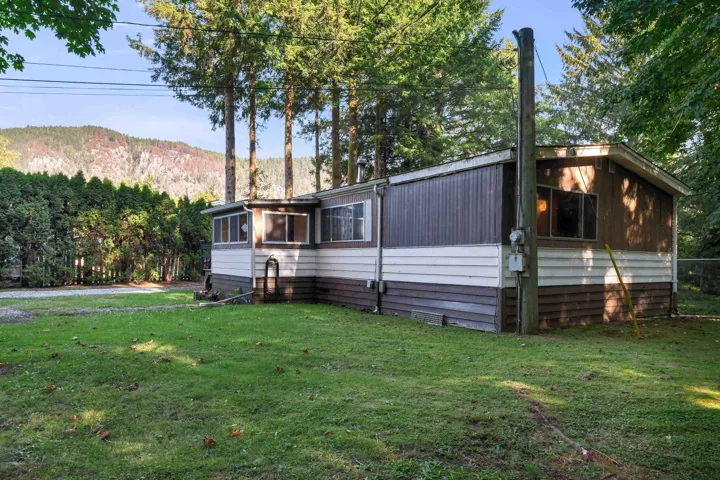 View of side of home with a yard, a forest view, and a mountain view
