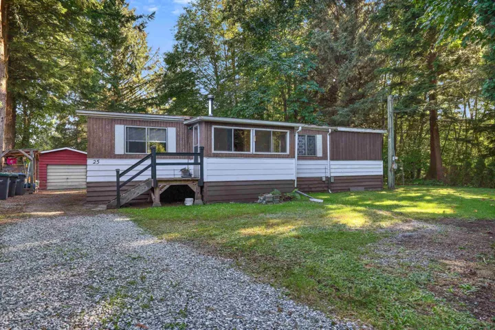 Manufactured / mobile home with an outdoor structure, driveway, a detached garage, and a front lawn