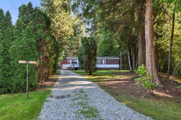 View of front of property featuring an outdoor structure and gravel driveway