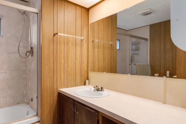 Full bathroom with vanity, shower / bath combination with glass door, and wood walls