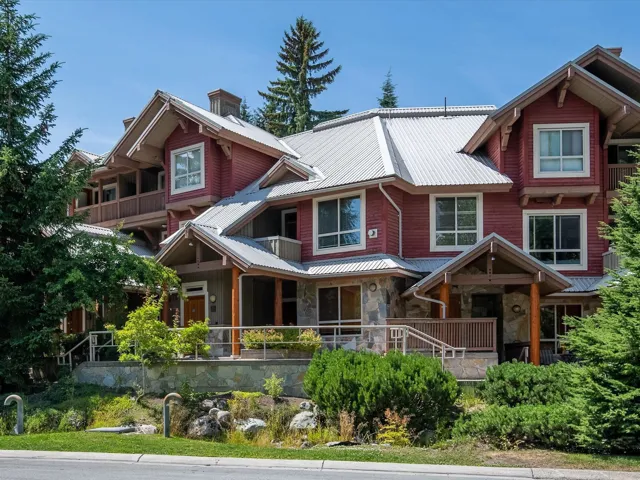 View of front facade featuring a chimney, stone siding, a balcony, and a metal roof