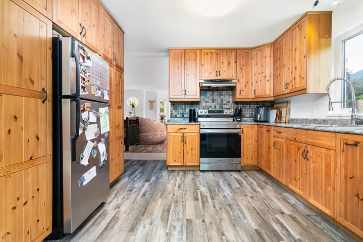 Kitchen featuring appliances with stainless steel finishes, light wood-style floors, under cabinet range hood, and decorative backsplash
