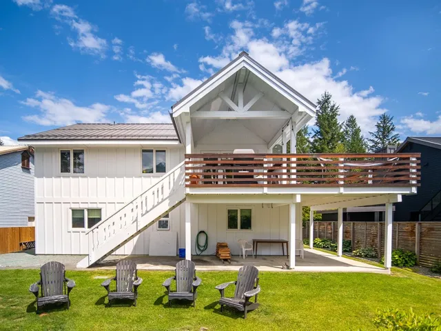 Back of property with board and batten siding, stairway, a patio, a metal roof, and a deck