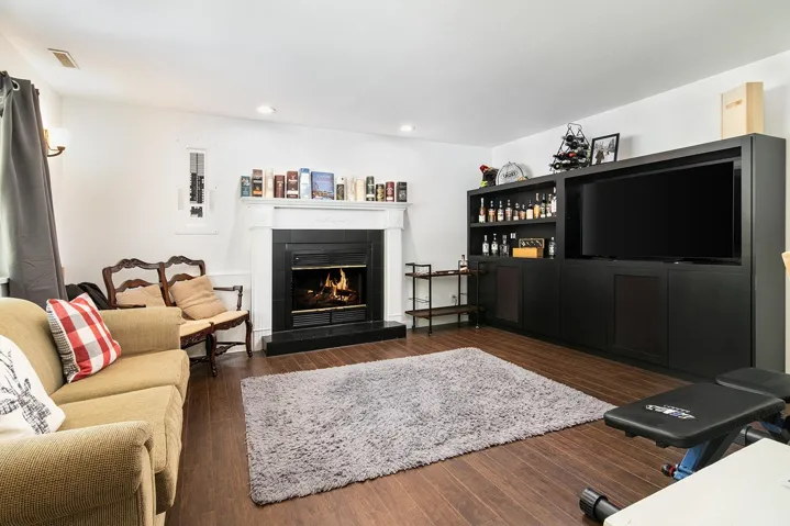 Living area with recessed lighting, a lit fireplace, and wood finished floors