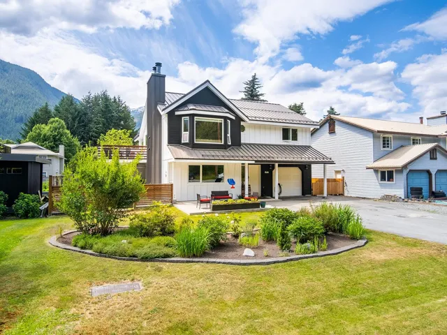 Modern inspired farmhouse with board and batten siding, a chimney, driveway, a standing seam roof, and a metal roof