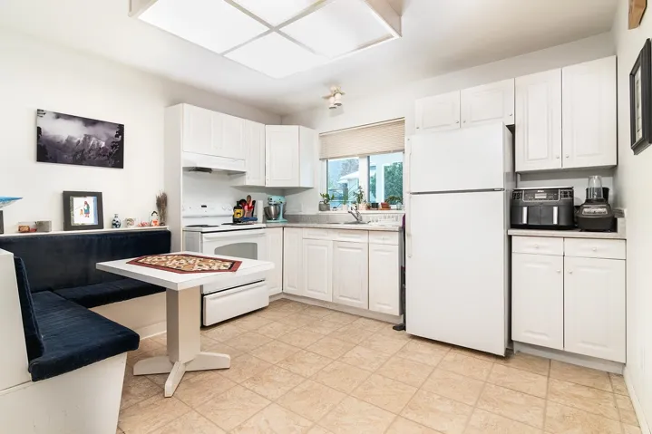 Kitchen with white appliances, under cabinet range hood, white cabinetry, and light countertops