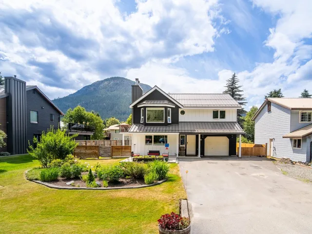 View of front of property featuring a standing seam roof, board and batten siding, a metal roof, asphalt driveway, and a mountain view