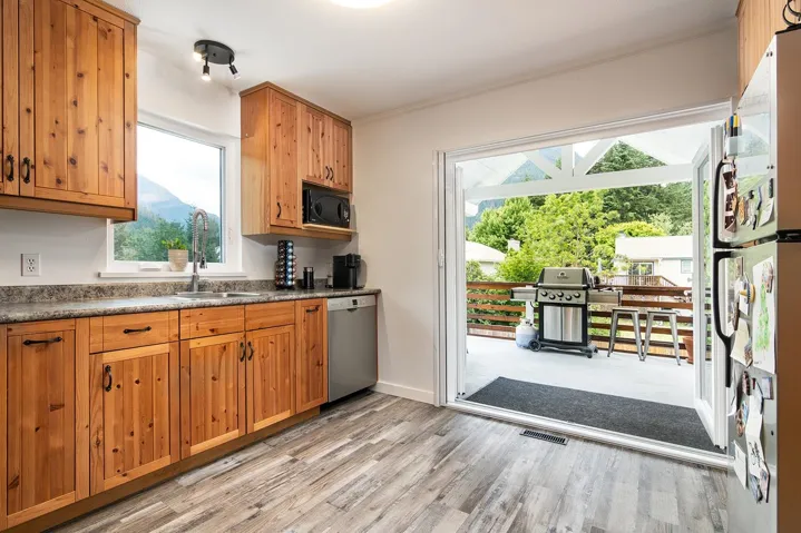 Kitchen featuring dishwasher, black microwave, light wood-style floors, freestanding refrigerator, and crown molding