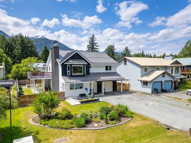 View of front of home featuring board and batten siding, a standing seam roof, a metal roof, a chimney, and driveway