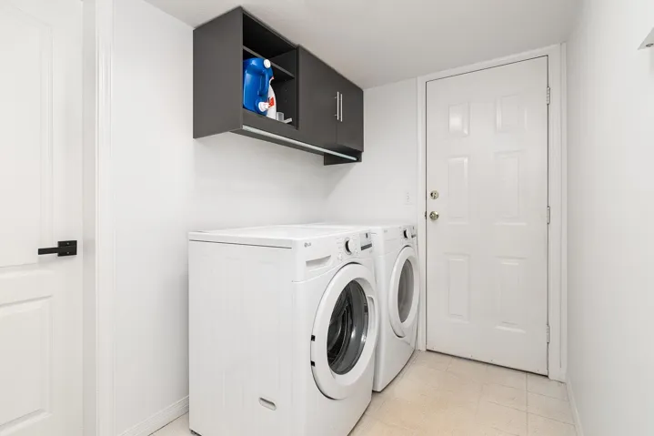 Washroom featuring washer and clothes dryer, cabinet space, and light floors