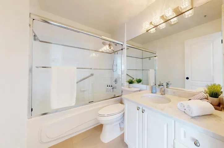 Bathroom with combined bath / shower with glass door, vanity, and light tile patterned floors