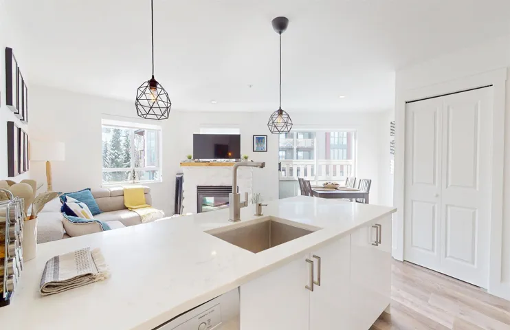 Kitchen with white cabinetry, hanging light fixtures, a high end fireplace, light wood-style floors, and open floor plan