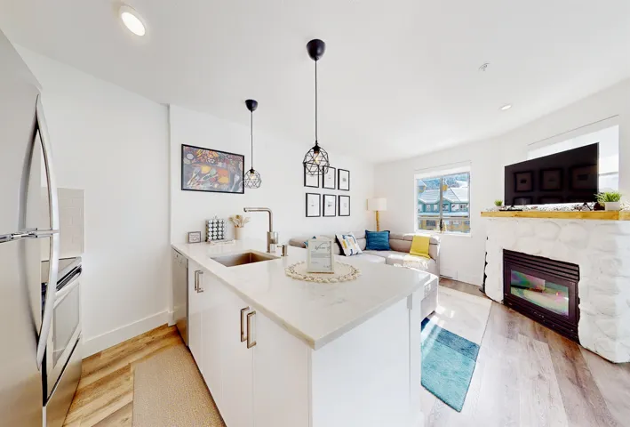 Kitchen featuring a peninsula, white cabinetry, stainless steel appliances, light wood-type flooring, and pendant lighting