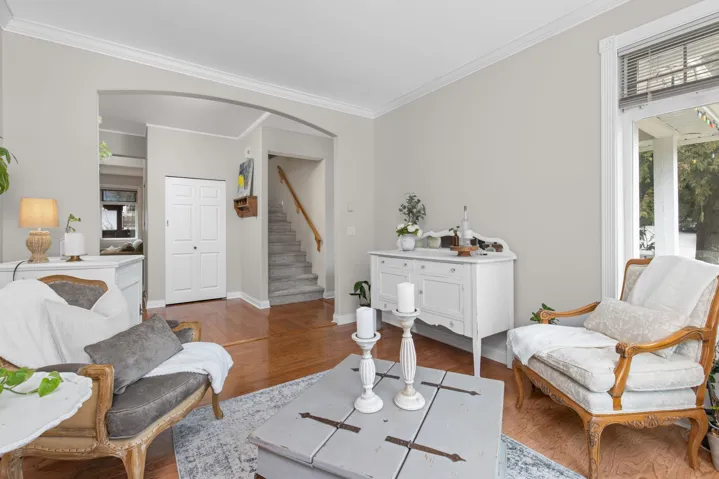 Living room featuring arched walkways, baseboards, wood finished floors, stairway, and ornamental molding