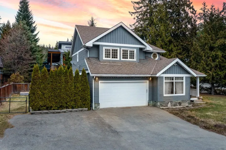 View of front of home with driveway, fence, roof with shingles, and board and batten siding