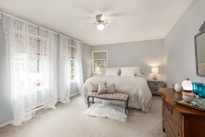 Bedroom featuring light colored carpet, baseboards, and a ceiling fan
