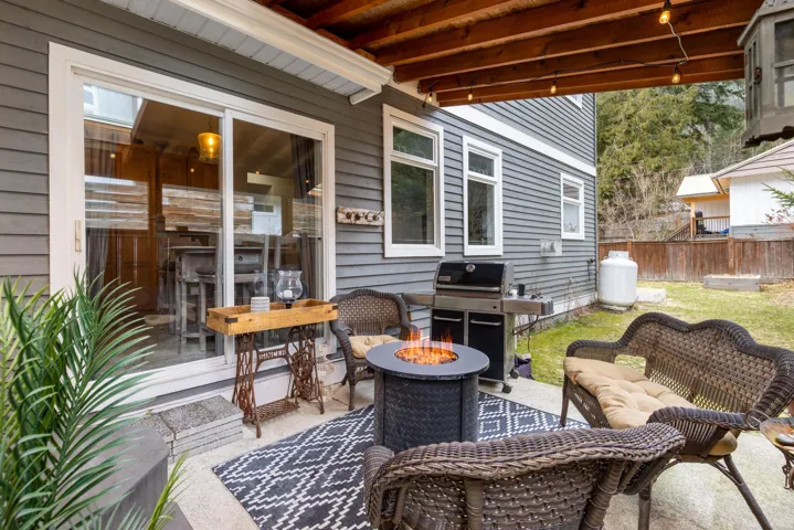 View of patio with fence, an outdoor living space with a fire pit, and area for grilling