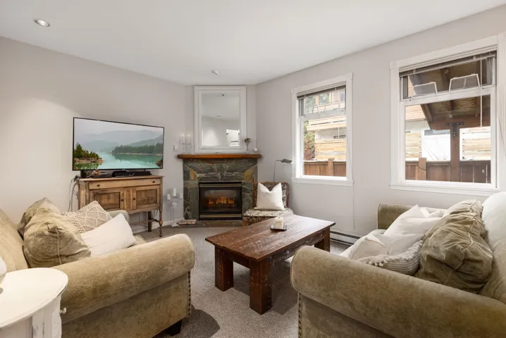 Carpeted living area featuring a baseboard heating unit, recessed lighting, and a fireplace
