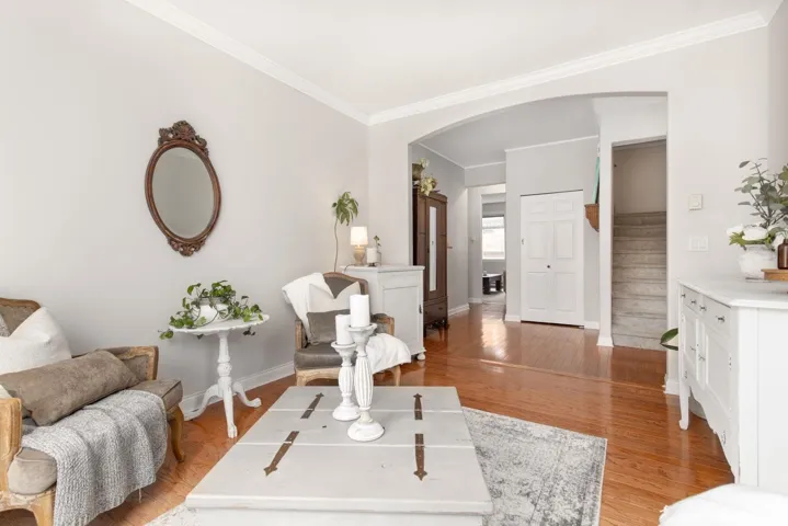 Living area with arched walkways, crown molding, stairs, and baseboards