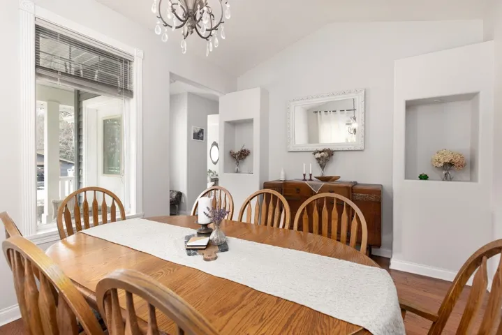 Dining room with baseboards, vaulted ceiling, wood finished floors, and a notable chandelier