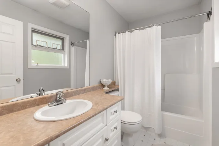 Full bath featuring tile patterned floors, toilet, visible vents, shower / bathtub combination with curtain, and vanity